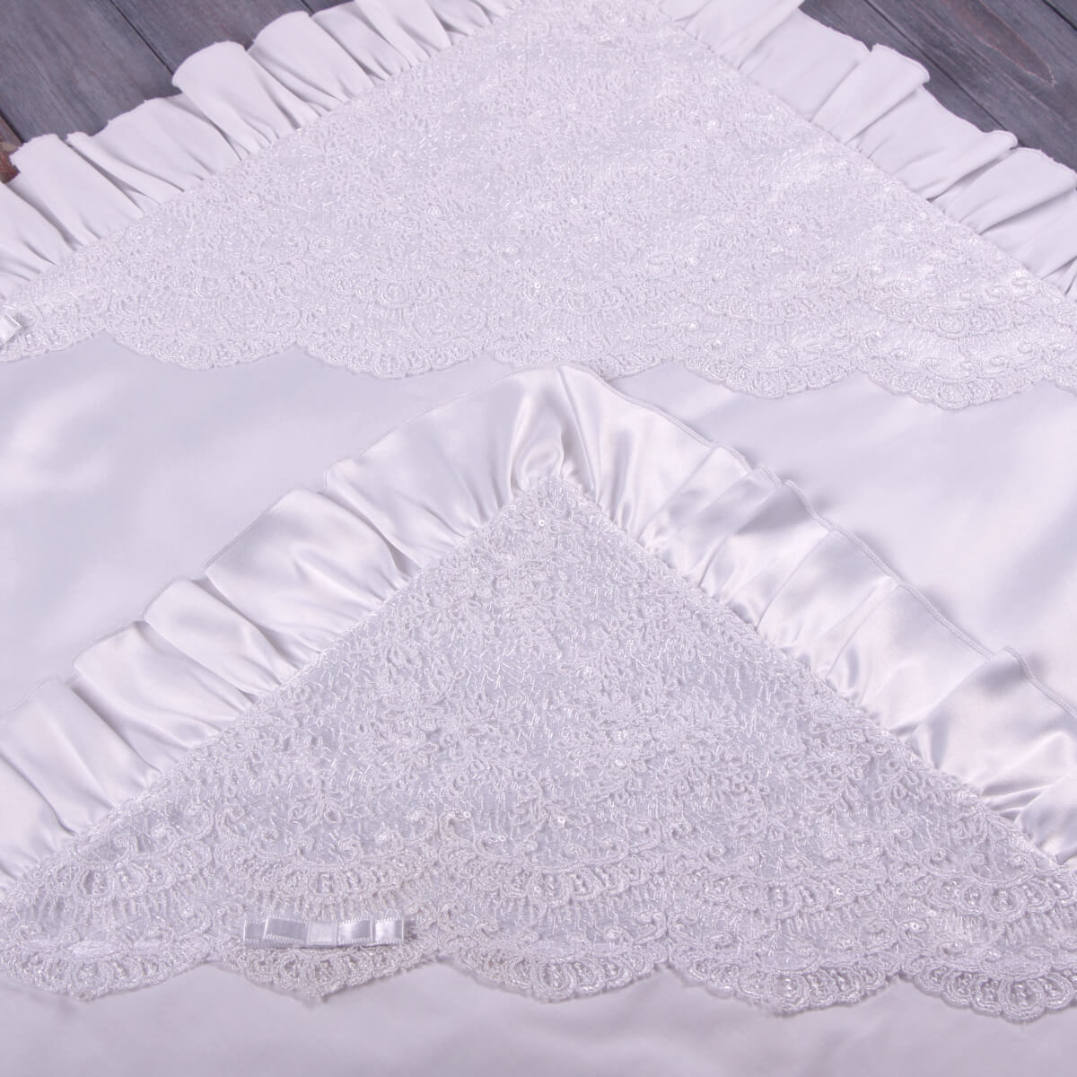 White textured christening blanket with lace trim on a wooden surface