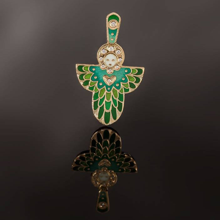 Baby angel pendant with green and gold design on a reflective black surface