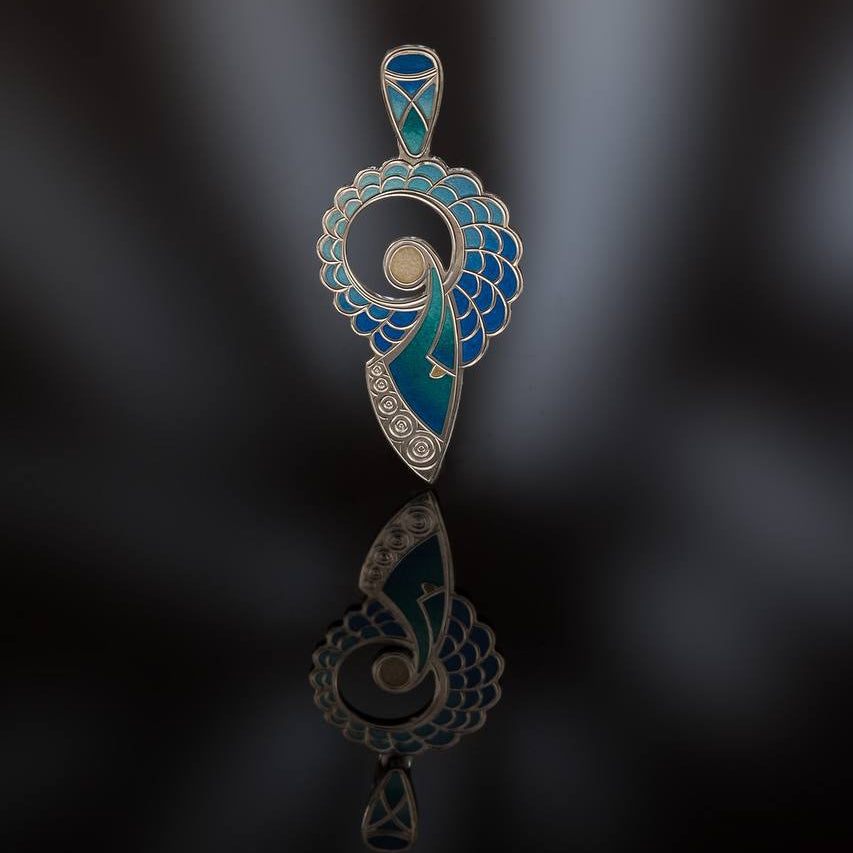 Decorative baby angel pendant with blue and silver design on a dark background