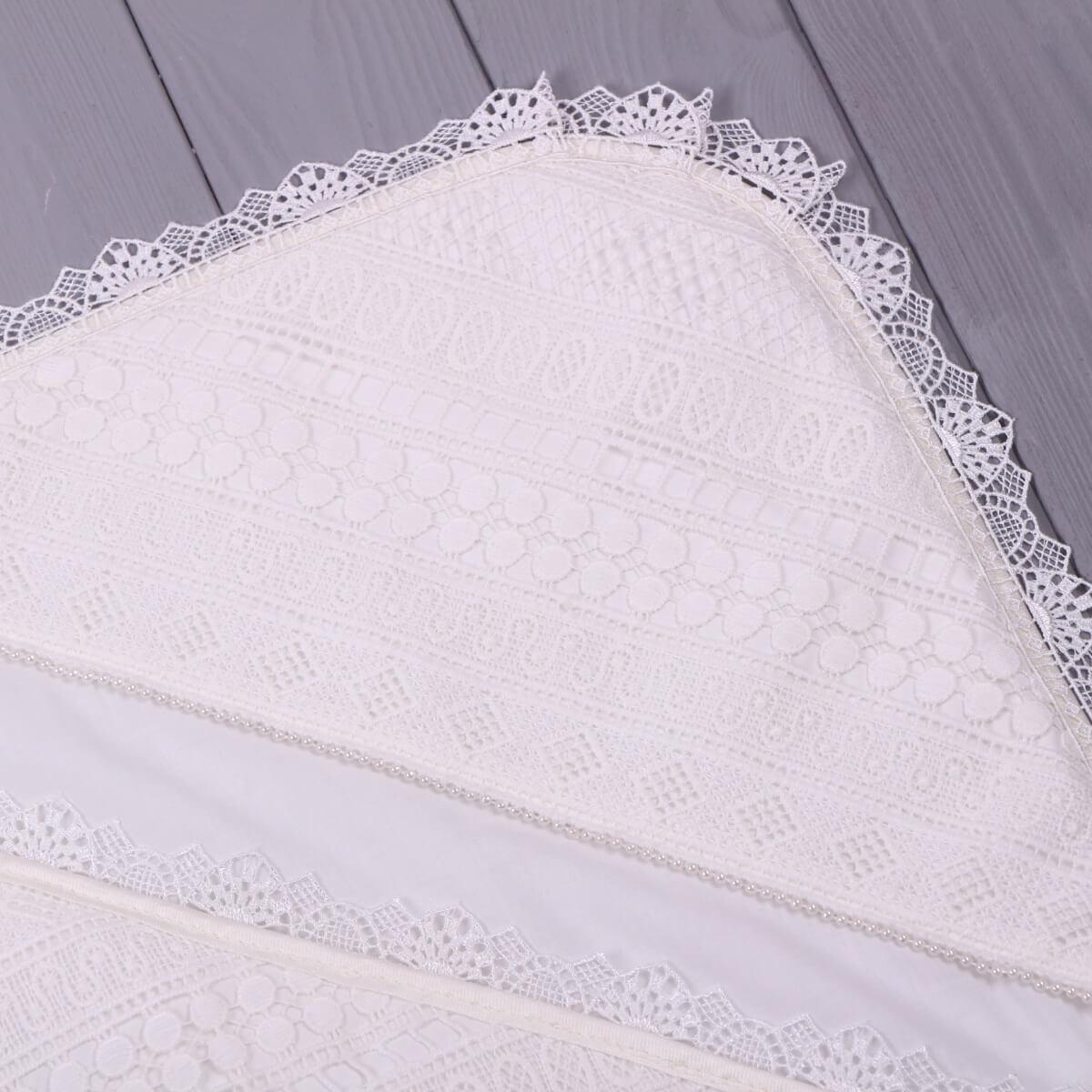 Baptism blanket with lace and personalization leo on a wooden surface