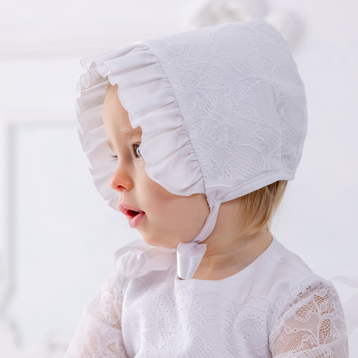 Baby wearing Christening Bonnet with lace details