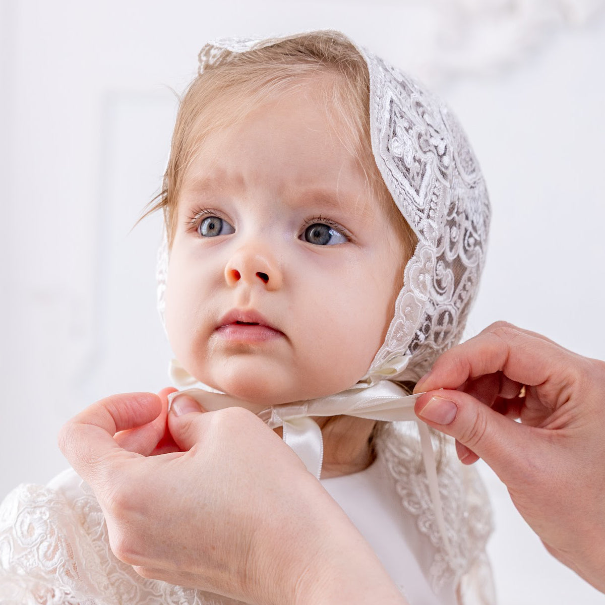 Baby in a lace baptism bonnet with a bonnet