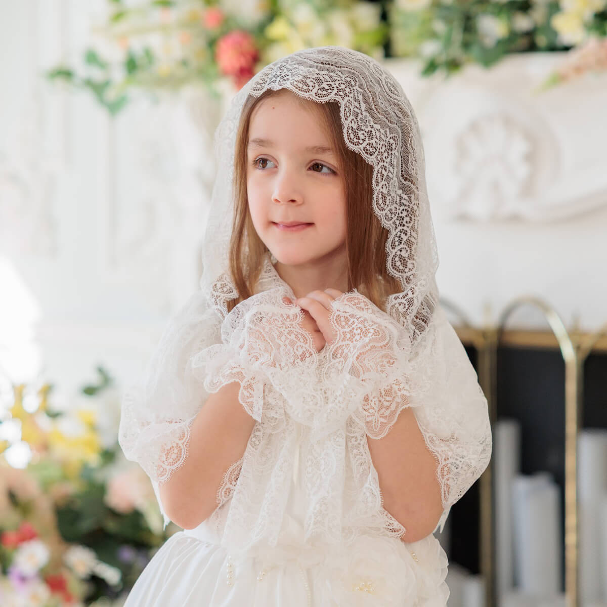 Young girl wearing a lace veil in a softly blurred indoor setting