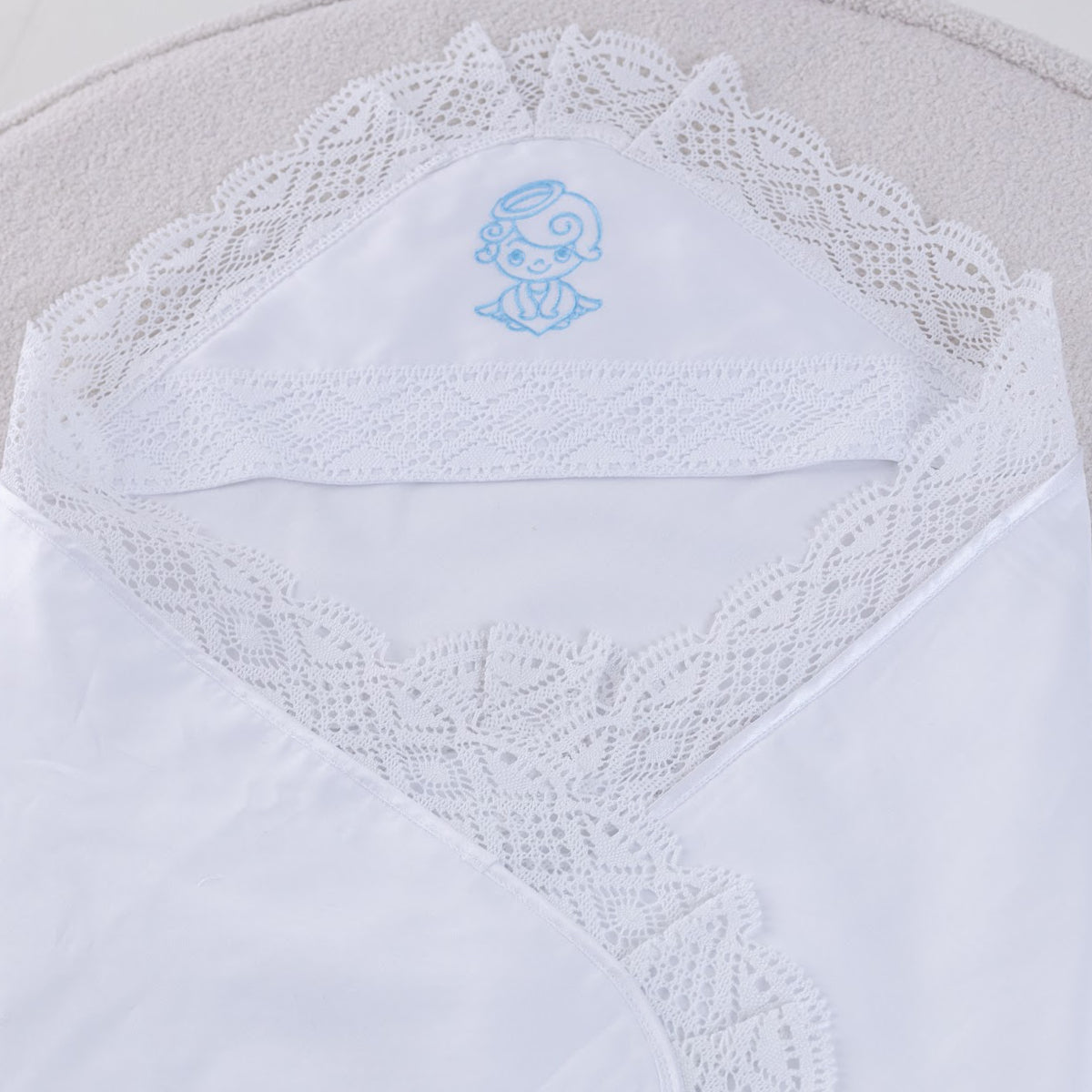 White lace-trimmed fabric with a small embroidered design on a light gray background