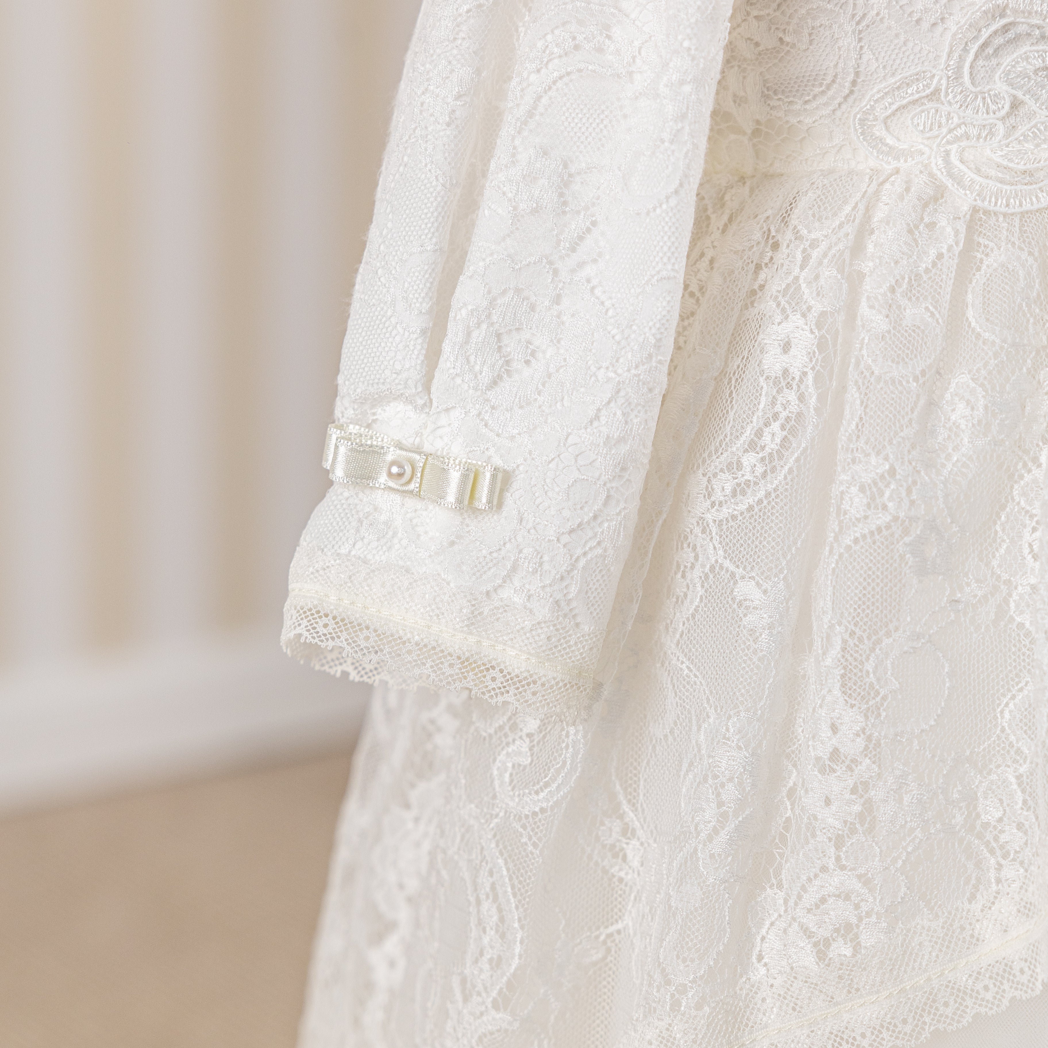 Close-up of a white lace garment with a brand label on a neutral background