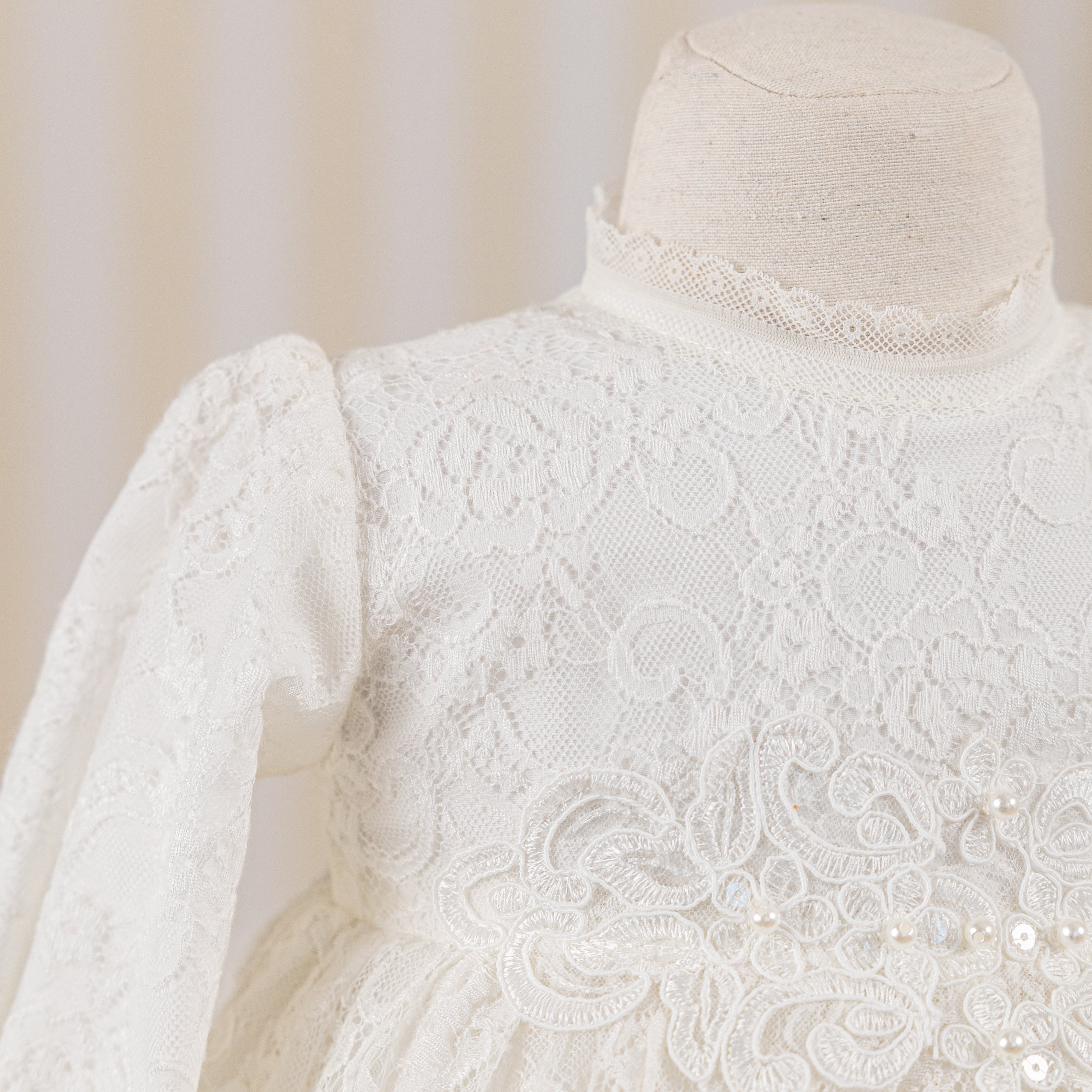 White lace dress on a mannequin against a neutral background