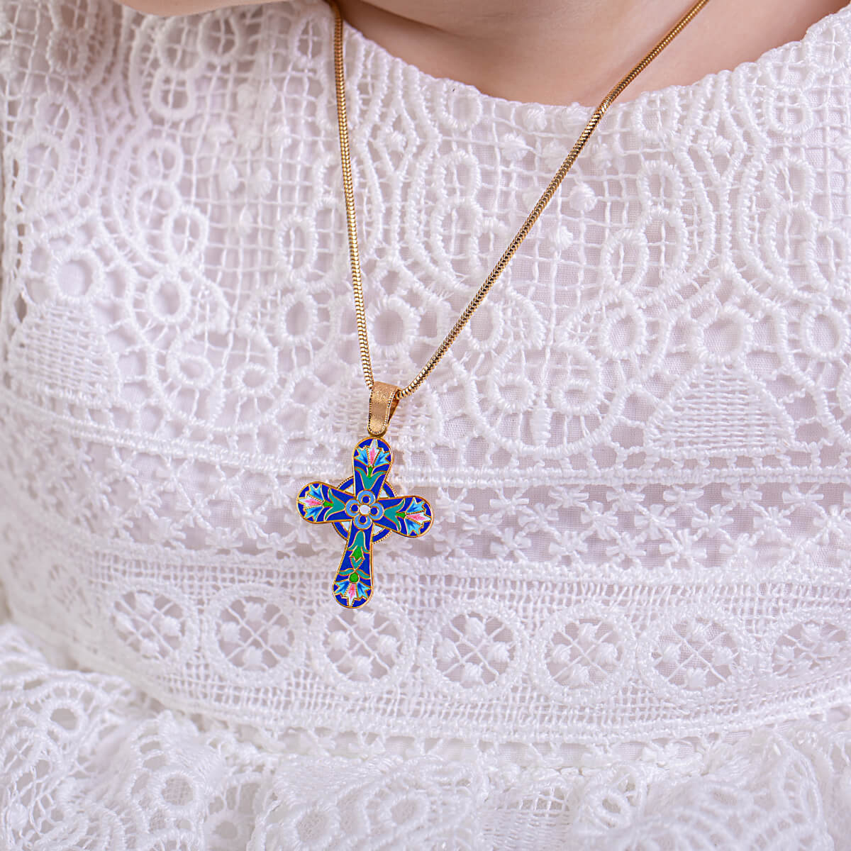 Necklace with a colorful cross pendant on a white lace background