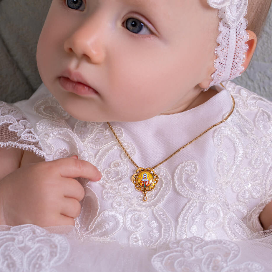 Baby in a white lace outfit with a gold necklace