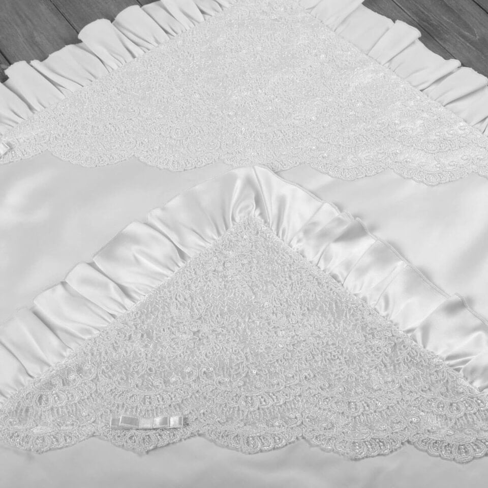 White textured blanket with lace trim on a wooden surface