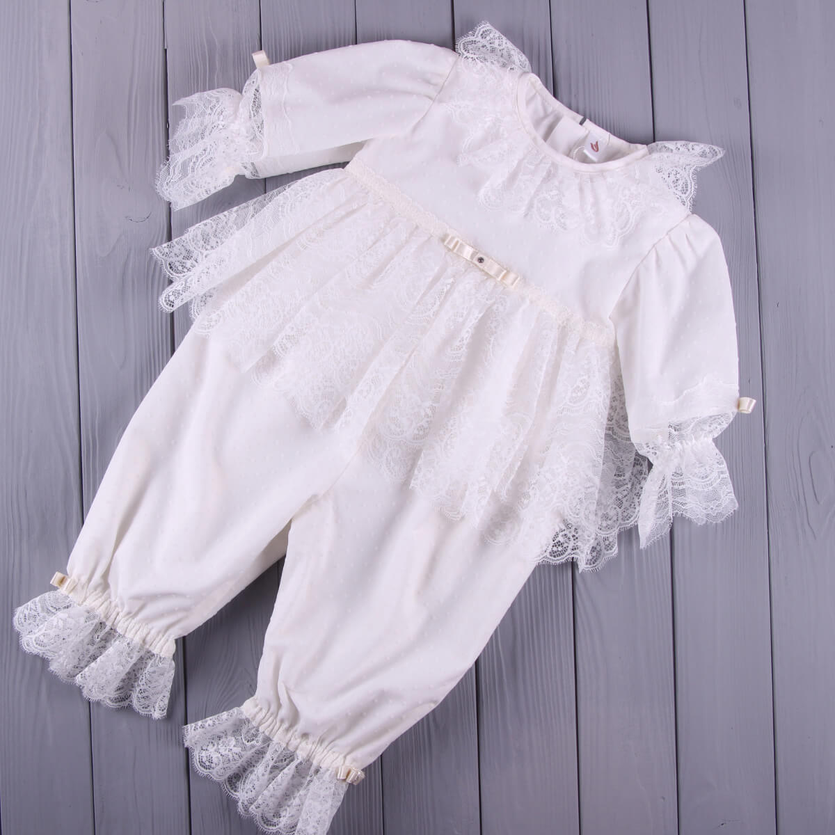 White lace christening rompern on a wooden surface