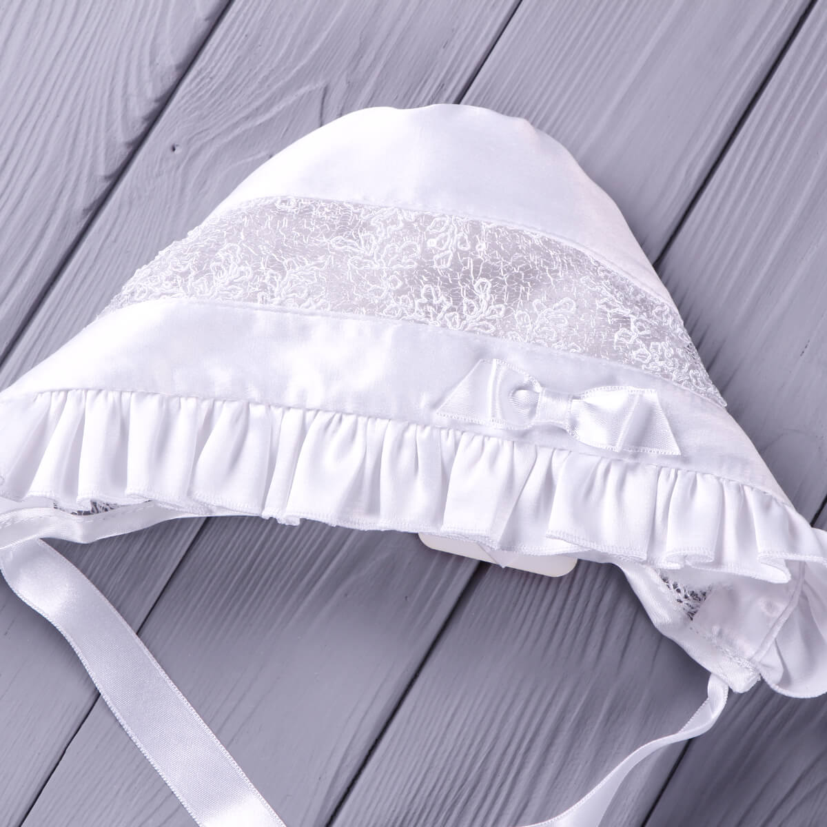 Silk Christening Bonnet on a wooden surface