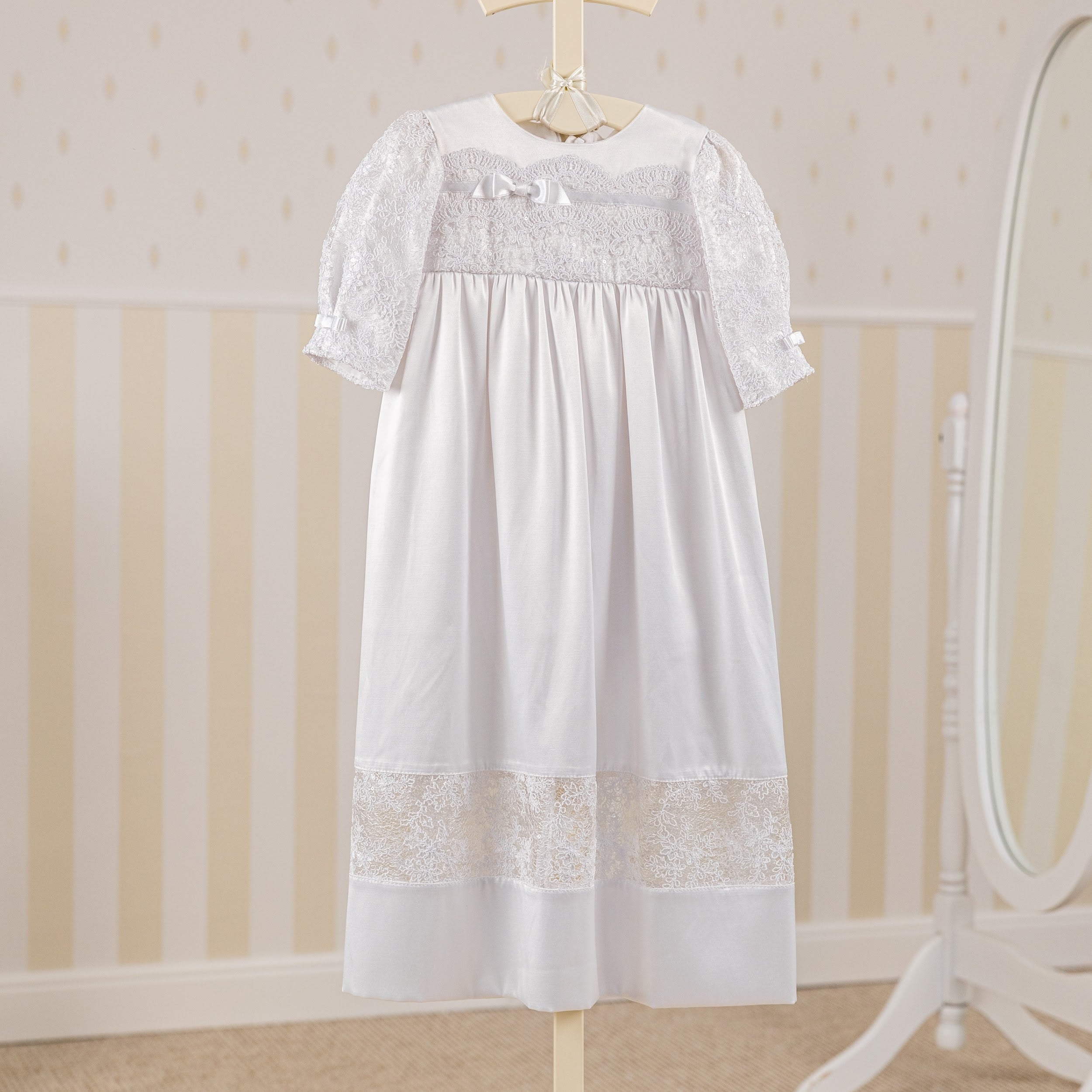 Christening Gown for Girls on a hanger against a neutral background