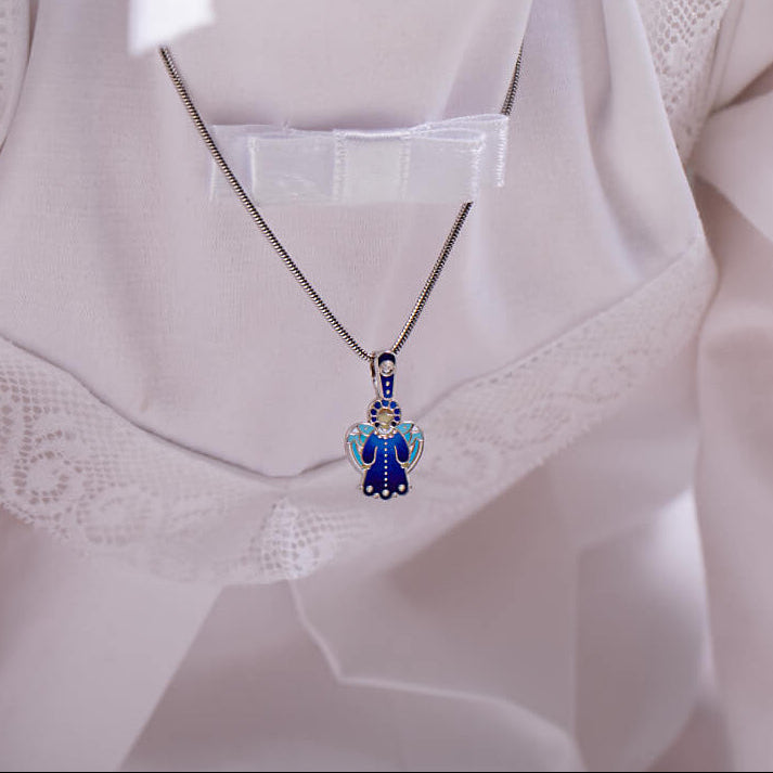 Close-up of a person wearing a white outfit with a necklace featuring a blue pendant.