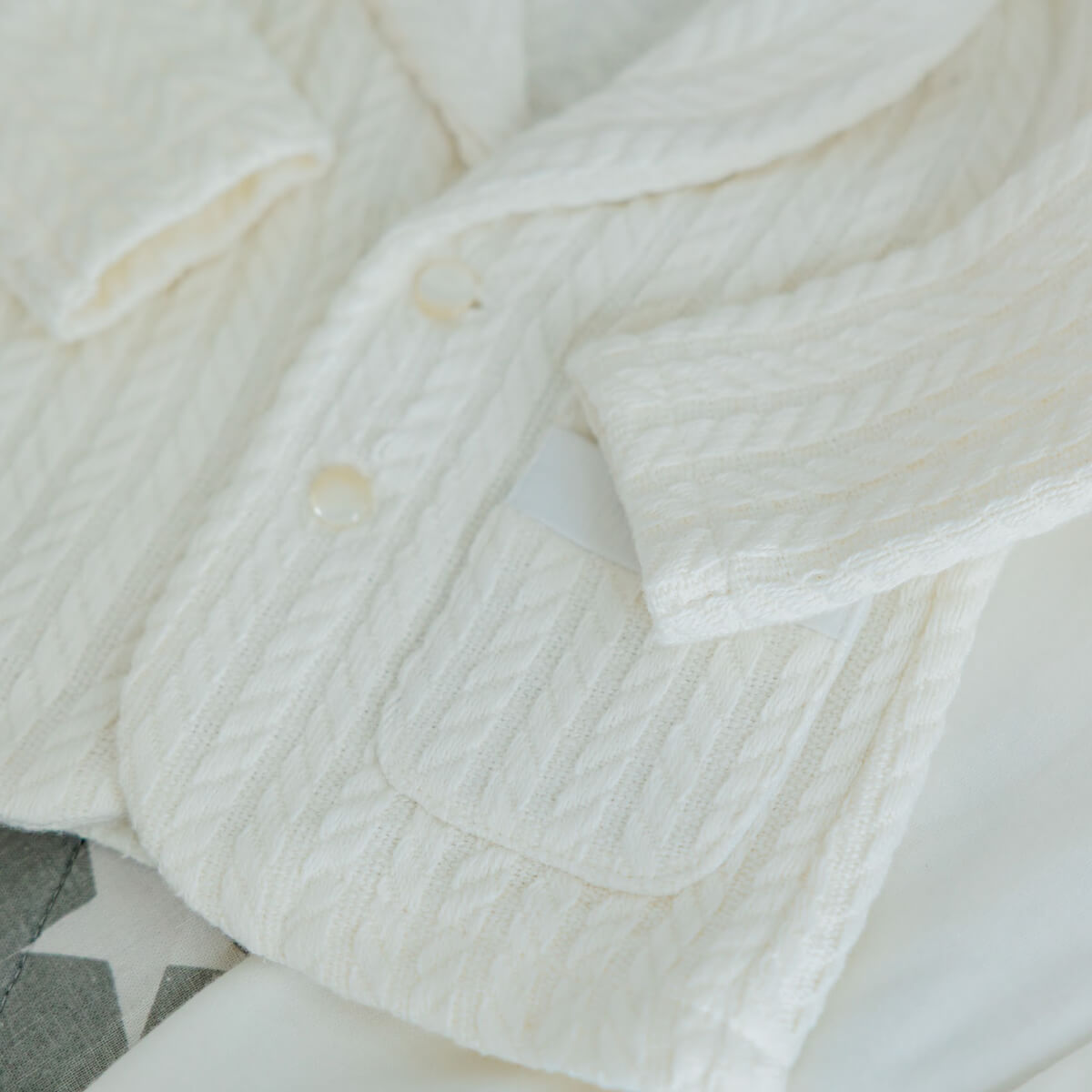 Close-up of a Newborn Coming Home Knit Set with a subtle pattern on a neutral background.