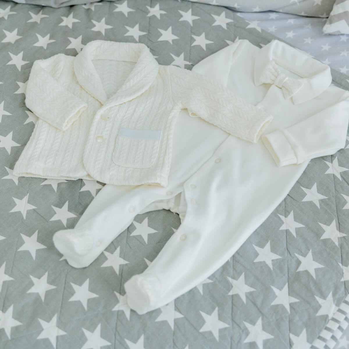Newborn Coming Home Knit Set on a bed with star-patterned bedding