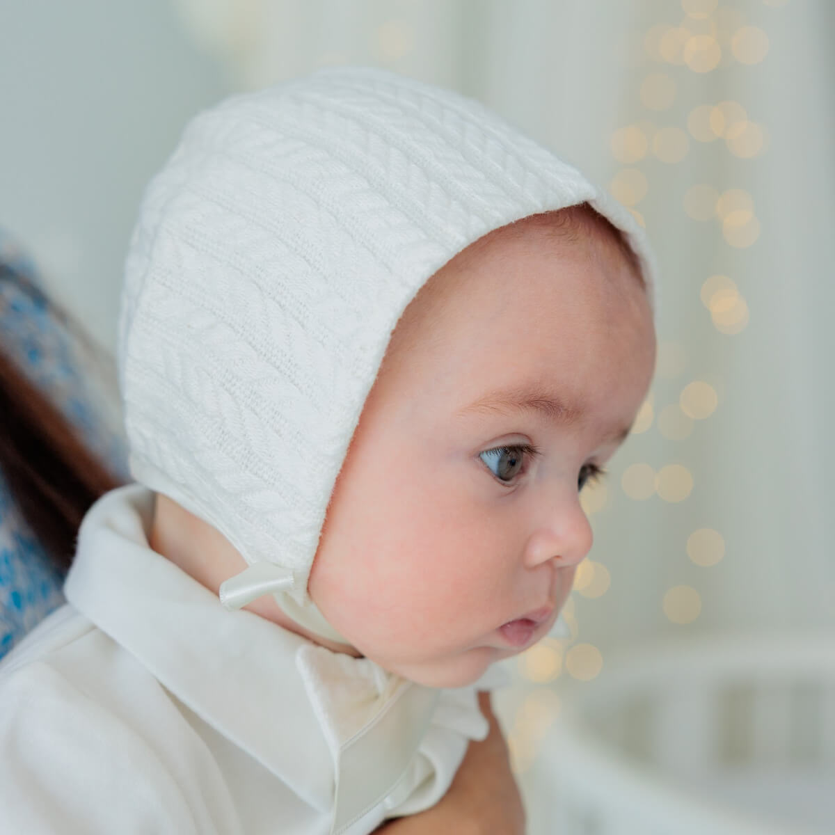 Baby wearing a Boy Baptism Hat with a blurred light background