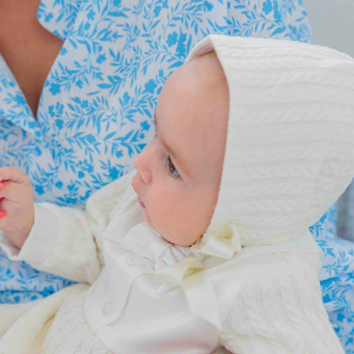 Baby in a Boy Baptism Hat with a floral-patterned fabric background