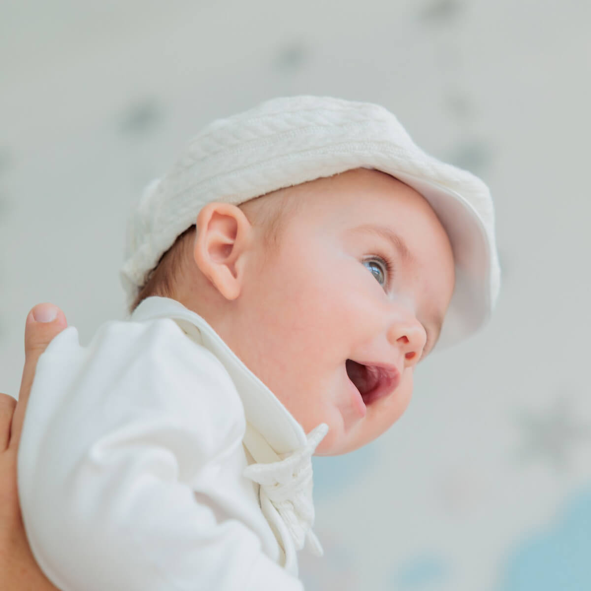 Baby wearing a Boy Christening Hat with a blurred background