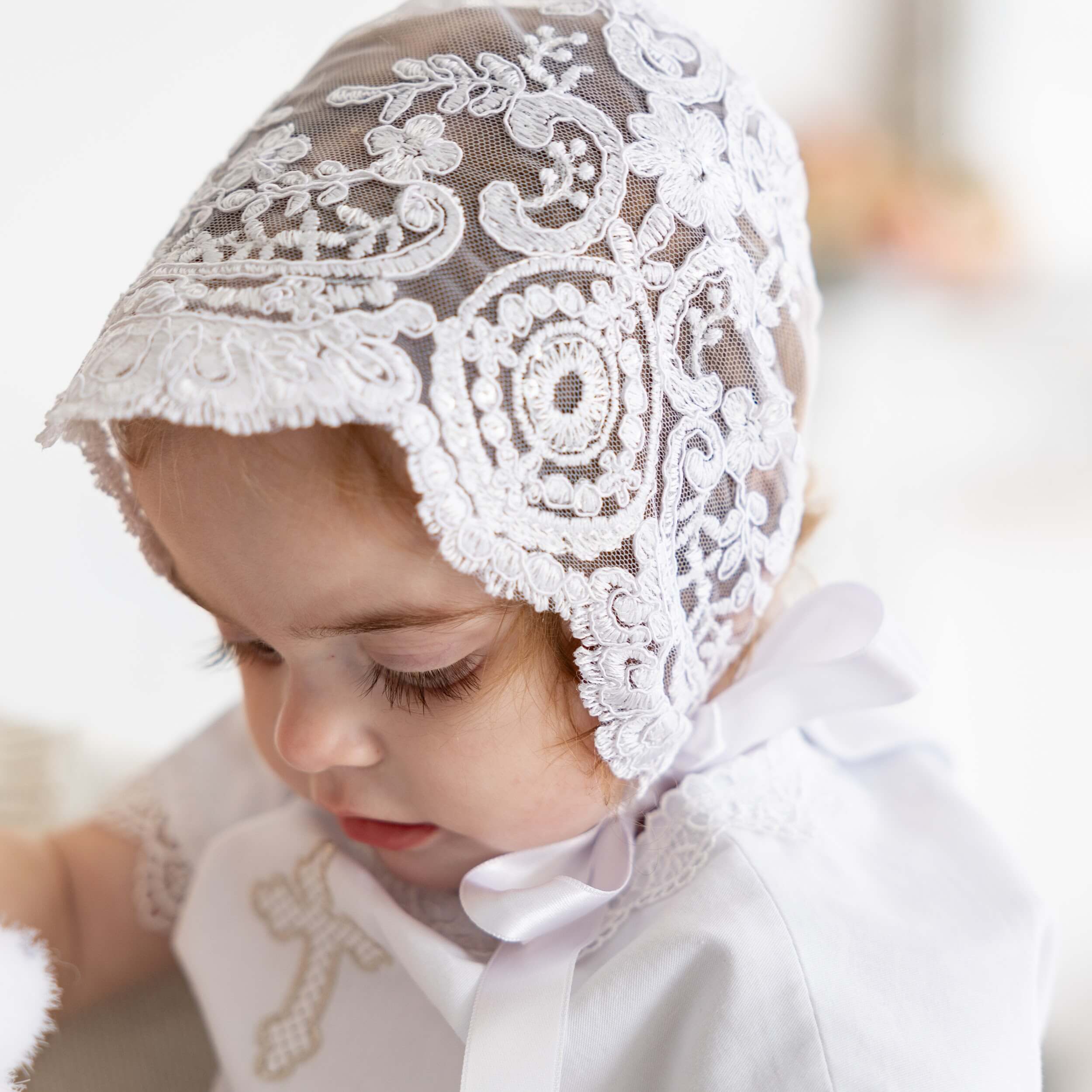 Child wearing a silk christening bonnet with a blurred background