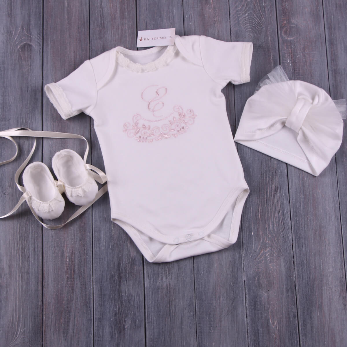 Baby Coming Home Bodysuit shoes, and hat on a wooden surface