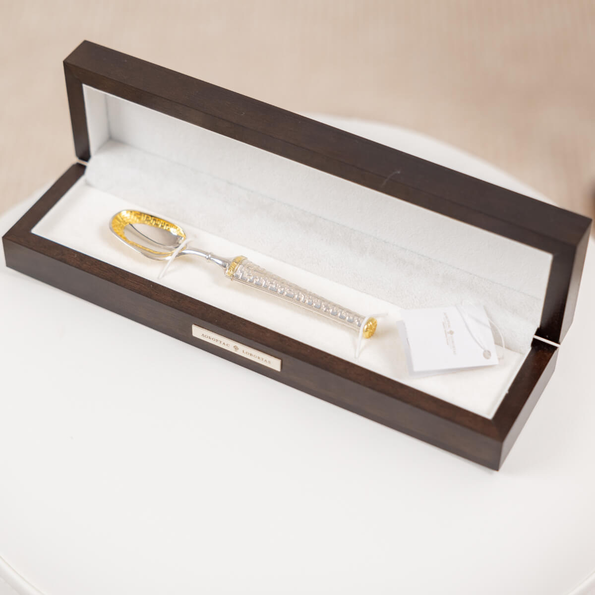 Baby silver and gold spoon set in a wooden box on a white surface