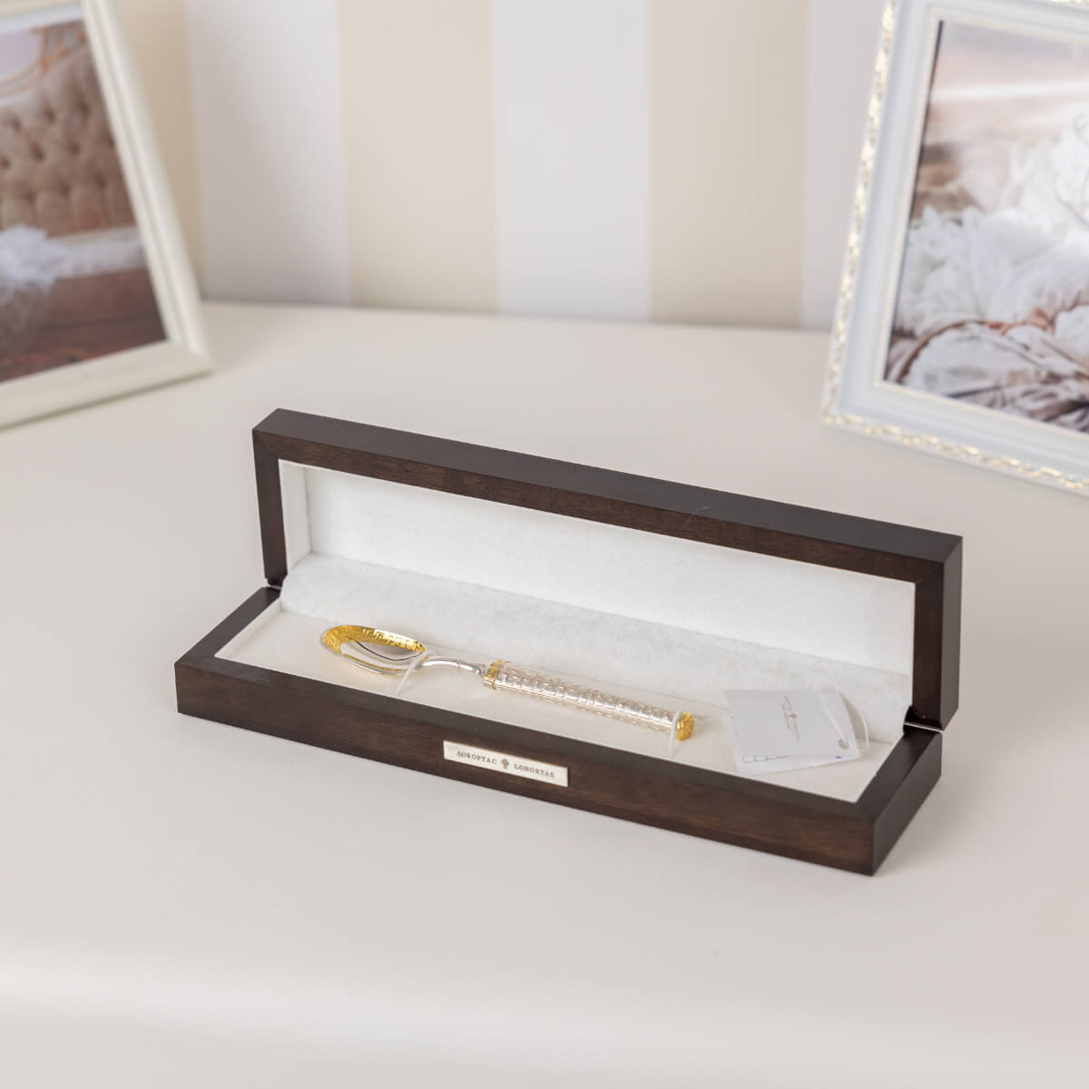 Gold-handled spoon in a wooden box on a light surface with blurred background