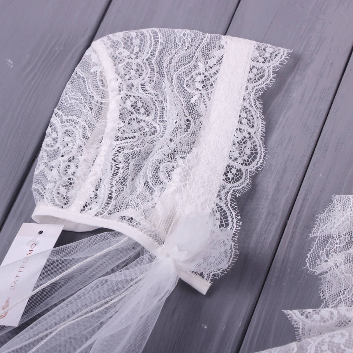Lace Baptism Bonnet on a wooden surface with a visible brand tag.