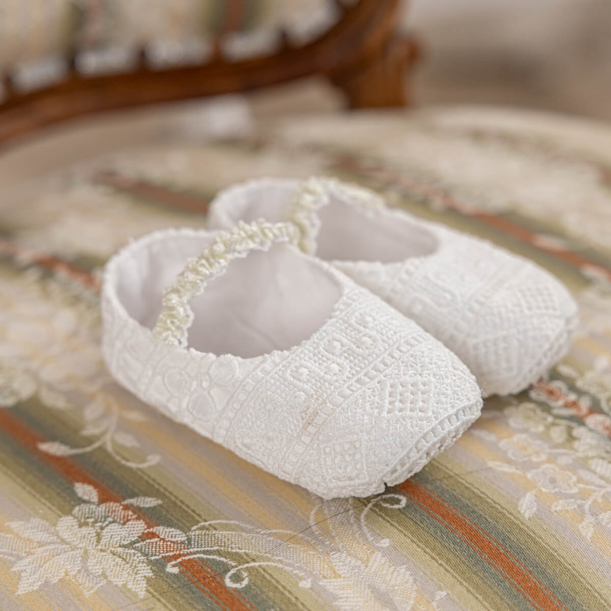 Pair of Christening Booties on a patterned surface