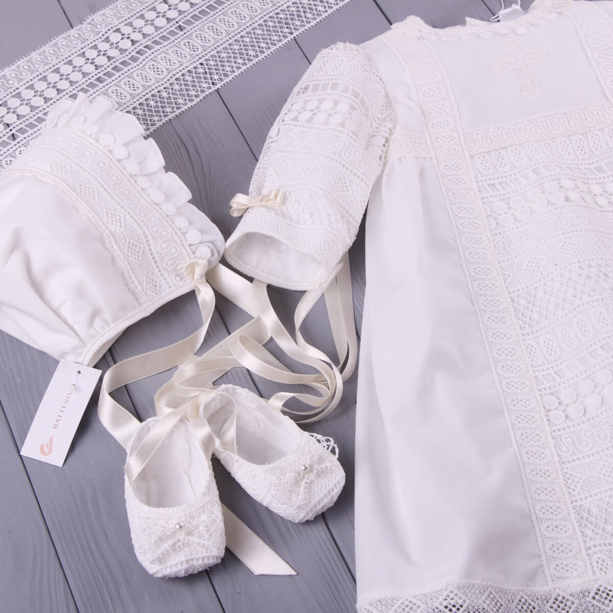 White lace baby outfit with lace christening bonnet on a wooden surface