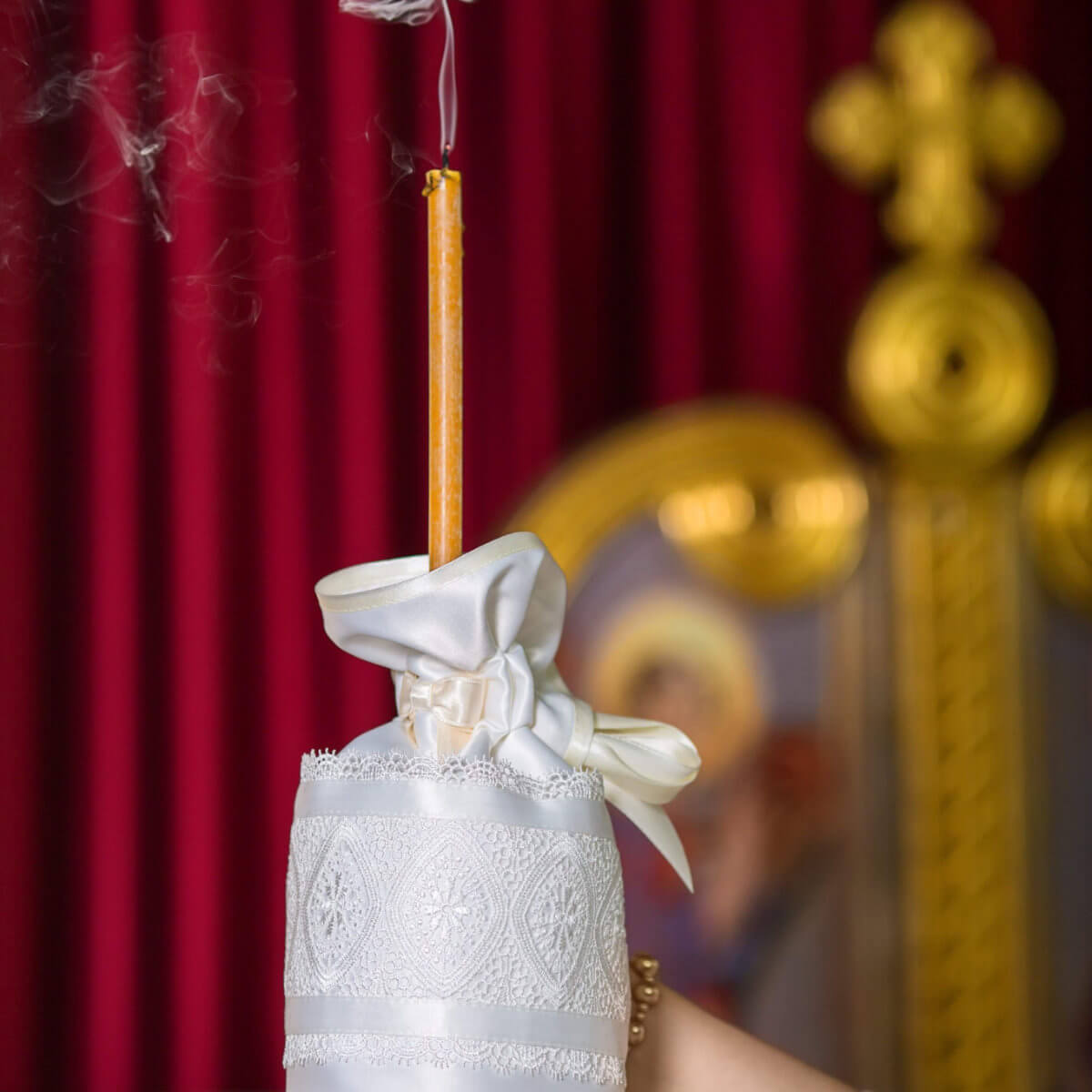 Candle Wraps with smoke in front of a blurred religious icon with red curtain background