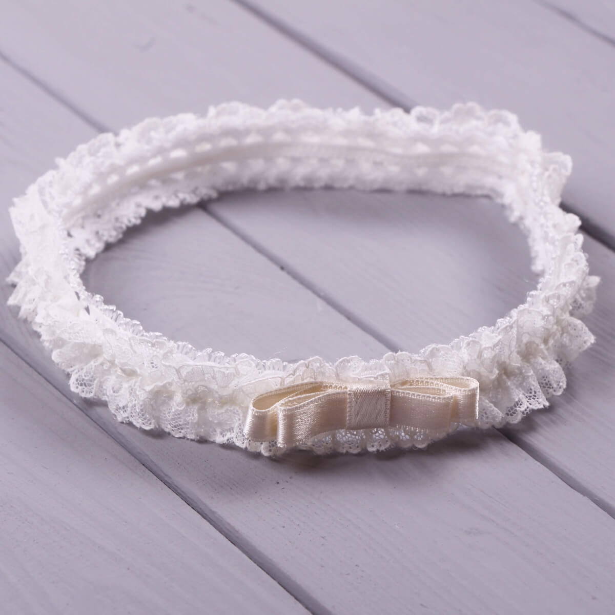 baby headband for baptism with a beige bow on a wooden surface
