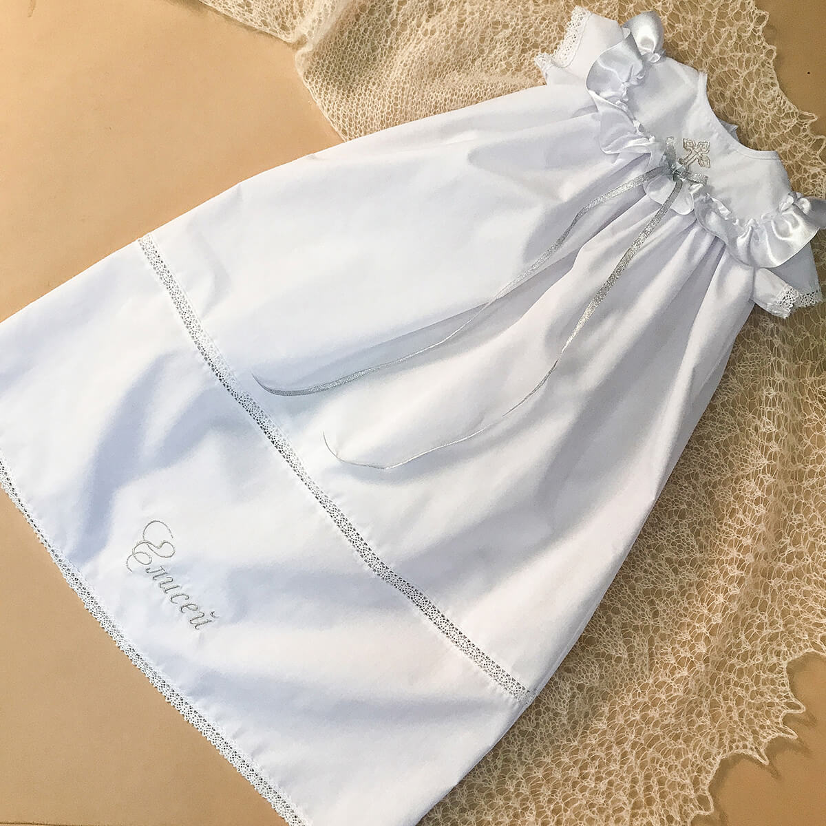 White christening long gown on a beige fabric background