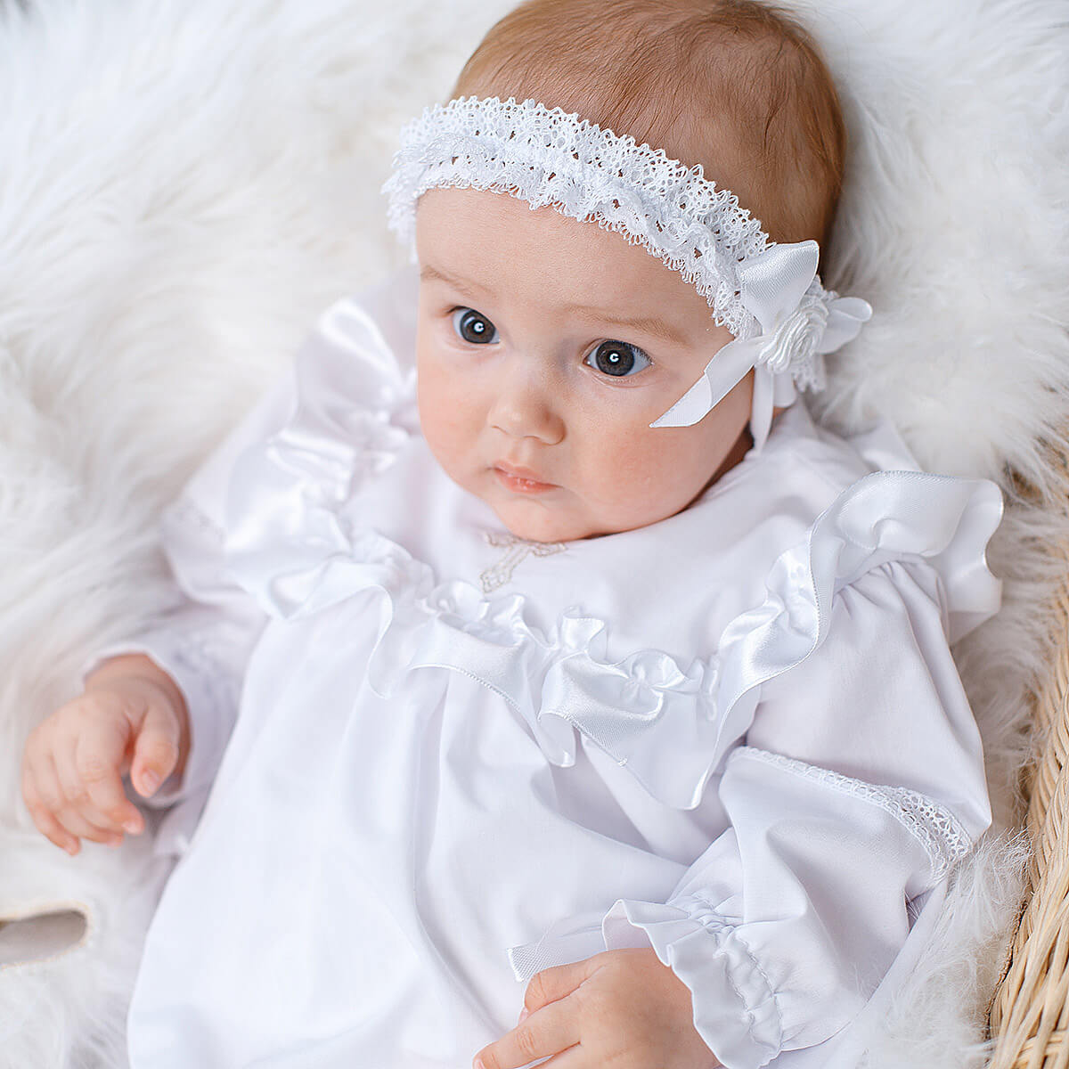 Baby in a Christening Gown for Girls with a lace headband on a soft white background