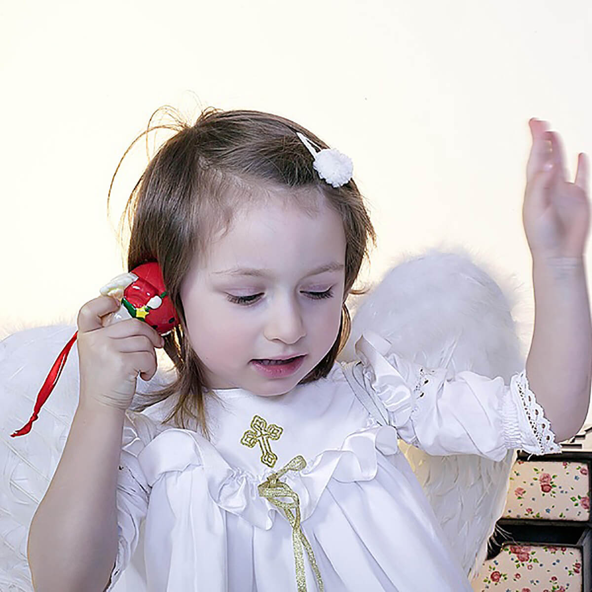 Young girl in an Christening Gown for Girls holding a red toy with a white background