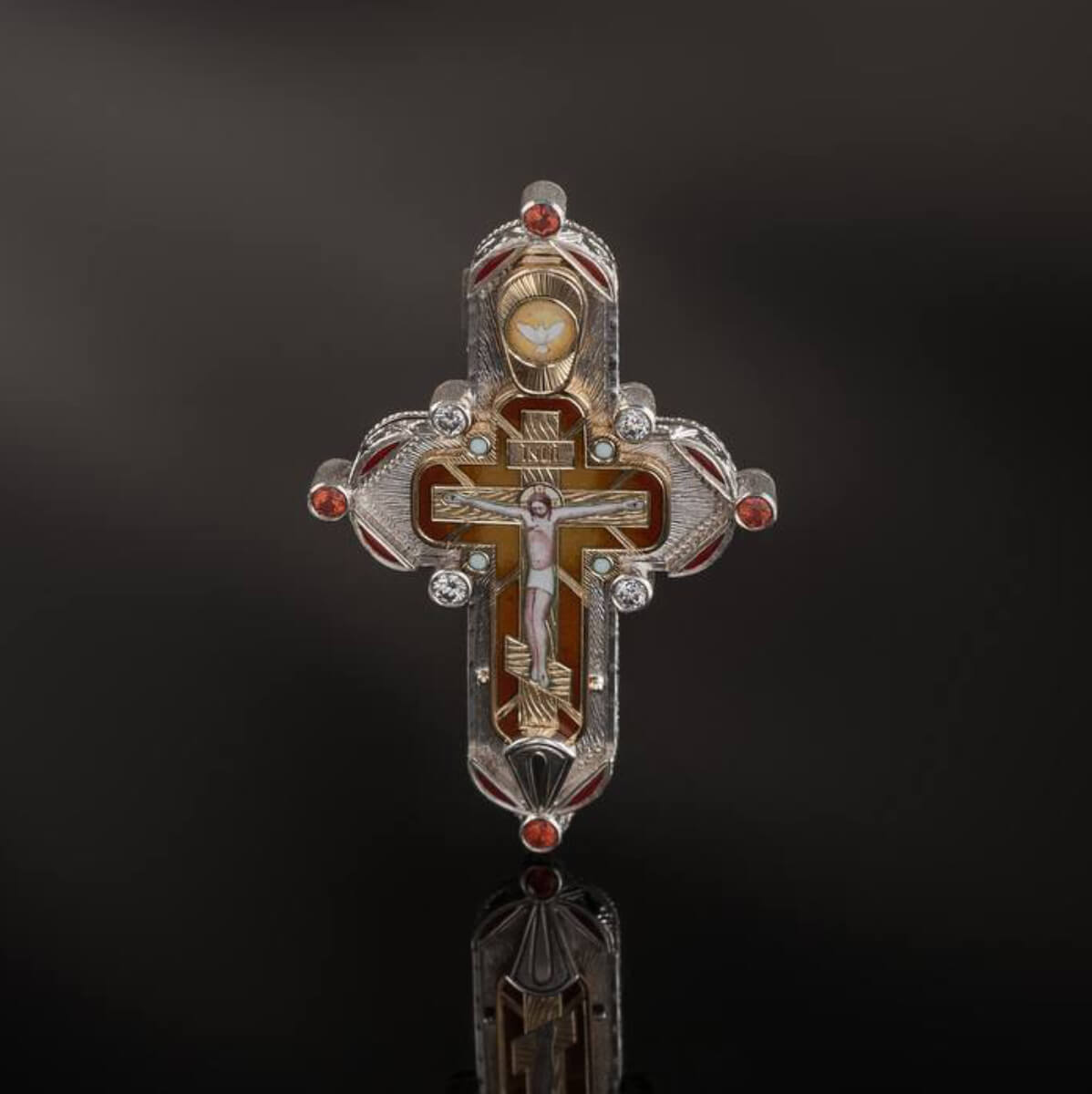 Decorative cross pendant with intricate design on a dark background