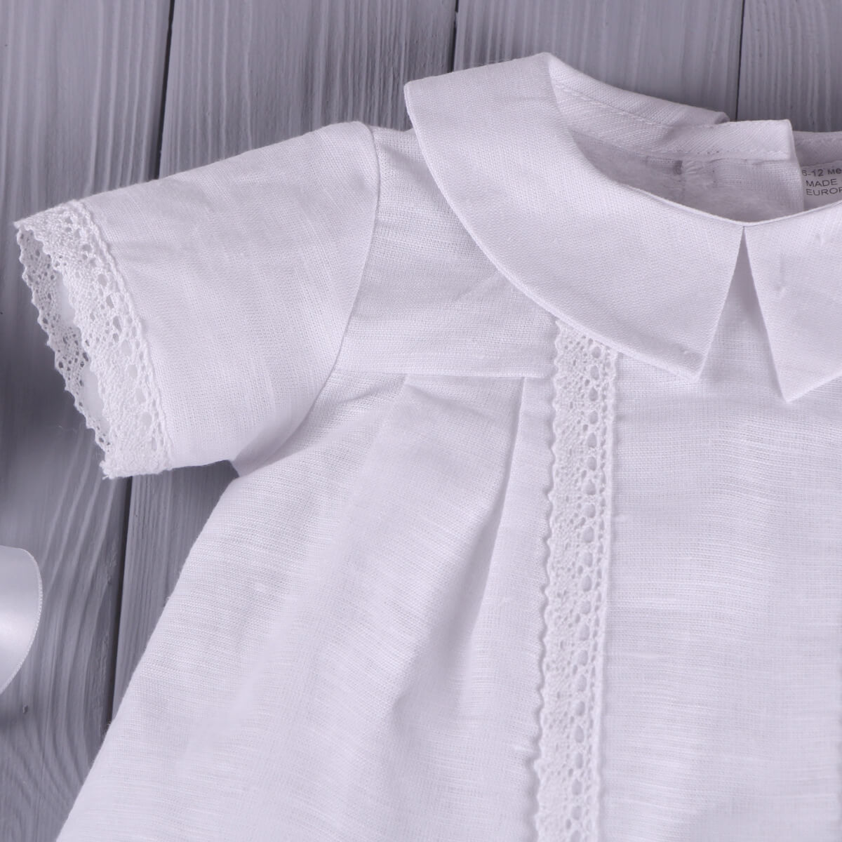 Baptism Outfit for Boys with lace details on a wooden surface