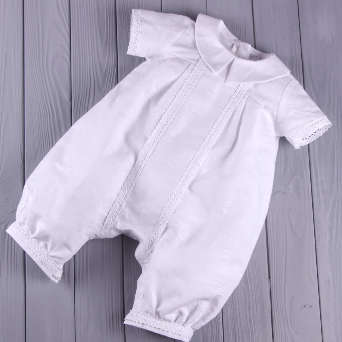 Baptism Outfit for Boys with lace details on a wooden surface