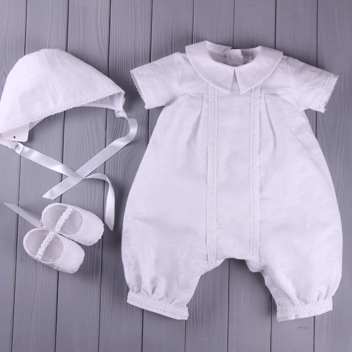 Baptism Outfit for Boys with bonnet and booties on a wooden surface