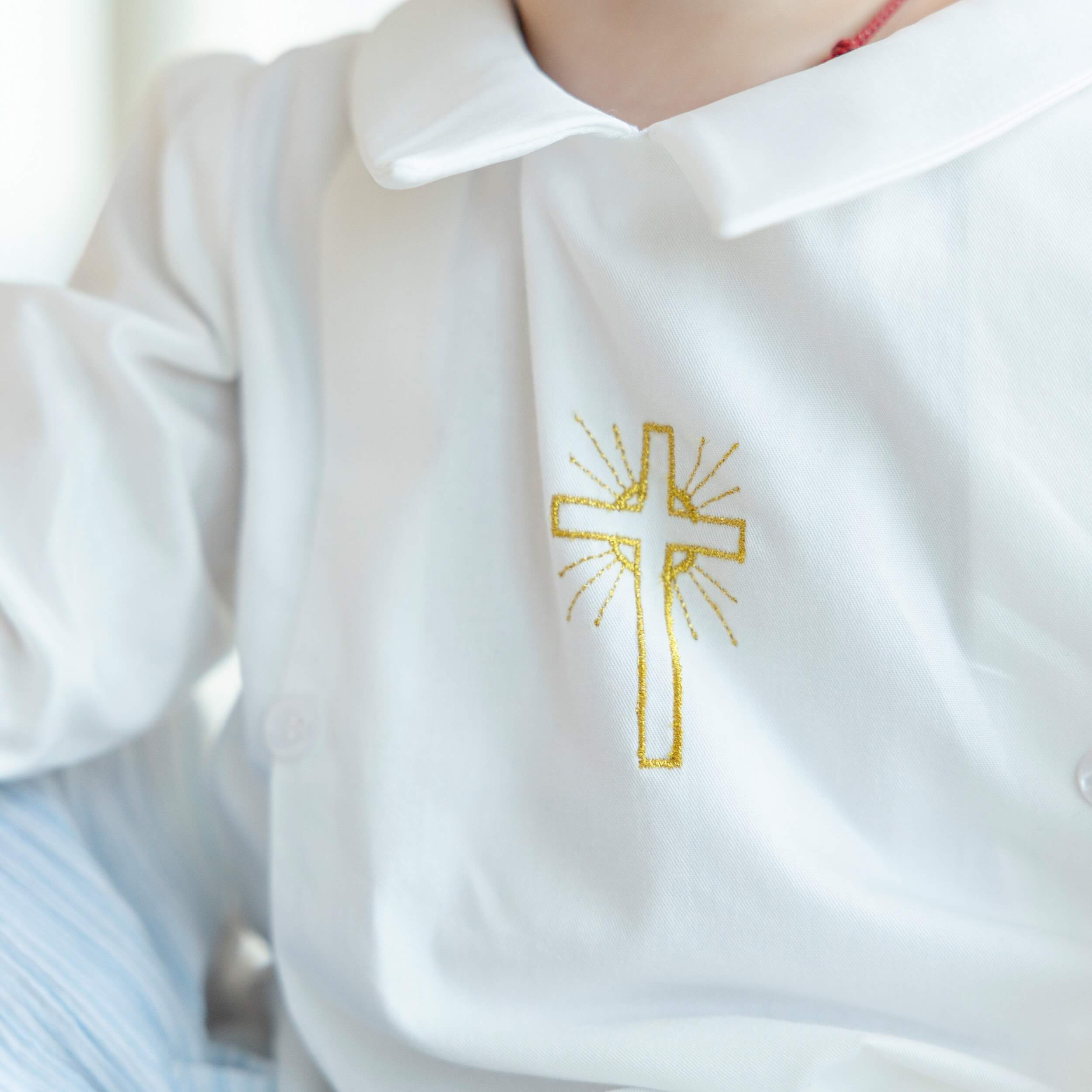 Baptism Gown with a gold cross embroidery on a blurred background