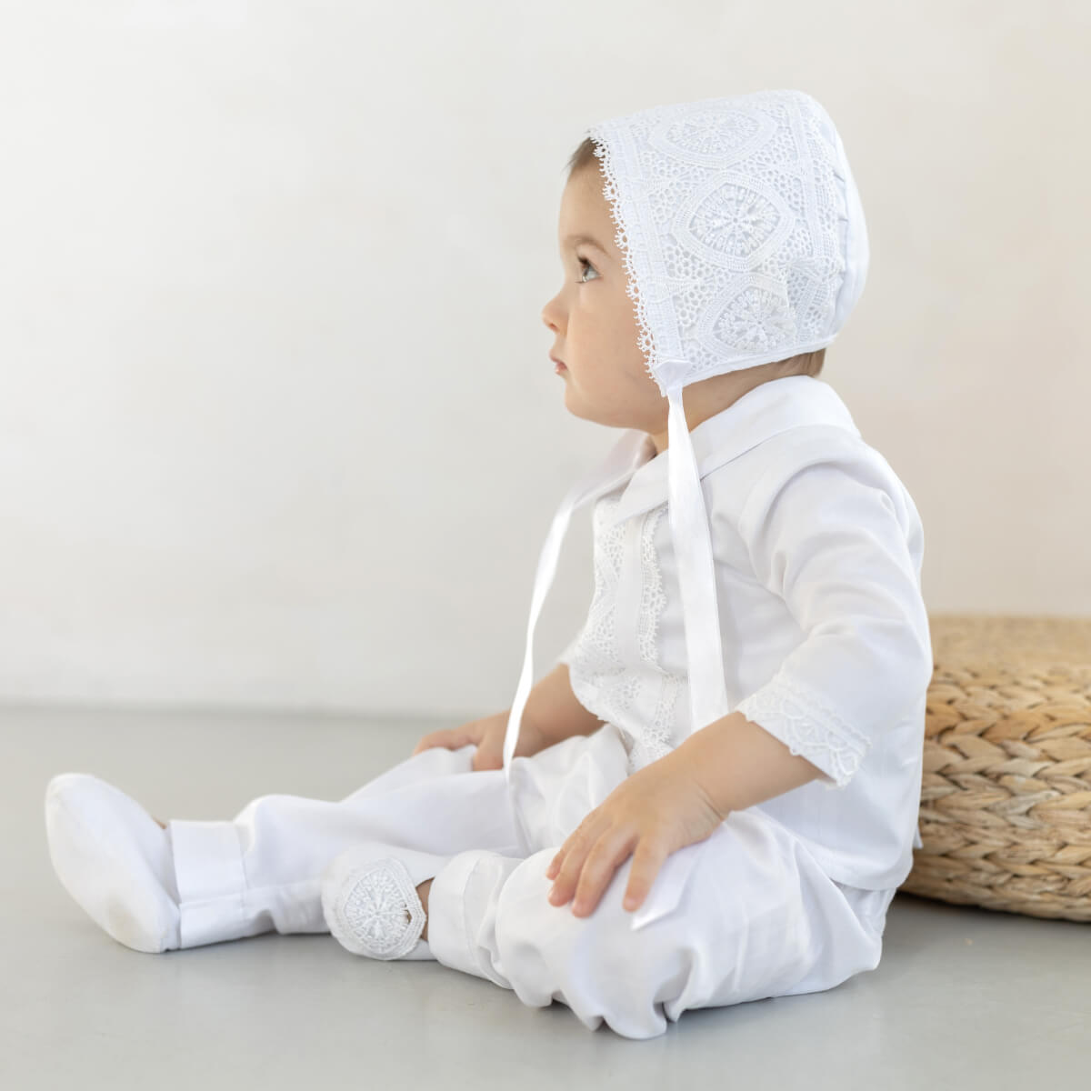 Baby wearing a Boy Baptism Hat sitting on a light surface.