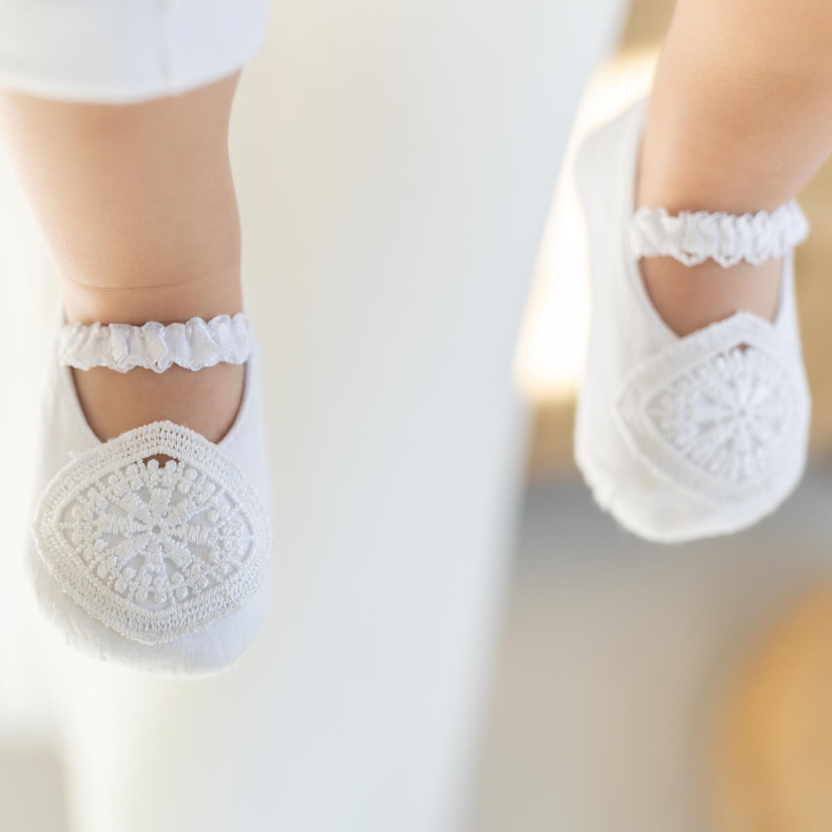 Baptism Booties with lace details on a blurred background