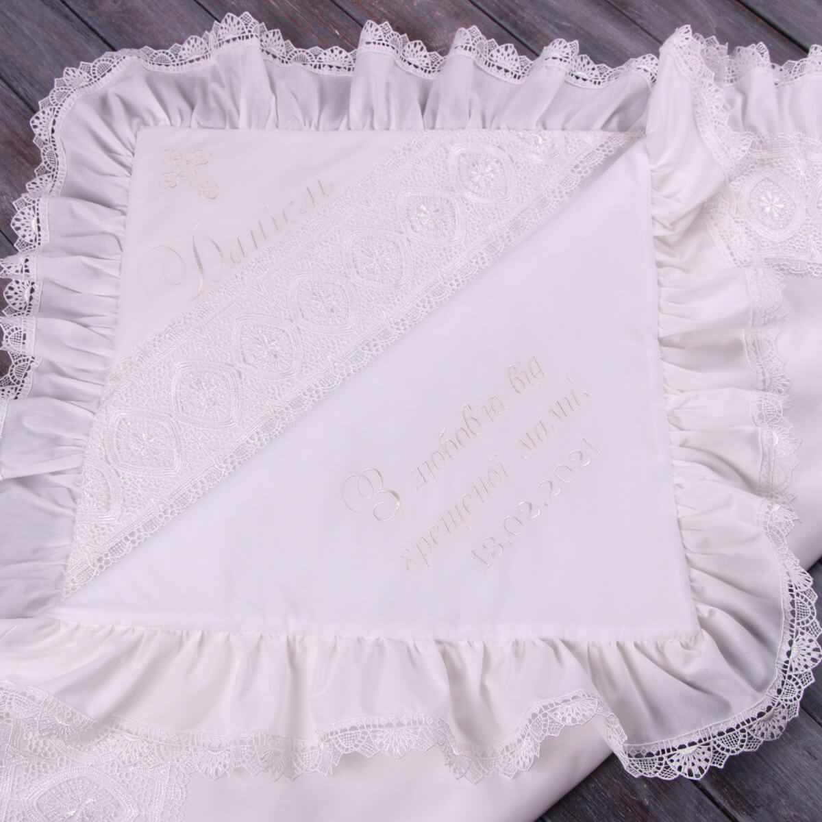 White lace-trimmed baptism blanket on a wooden surface