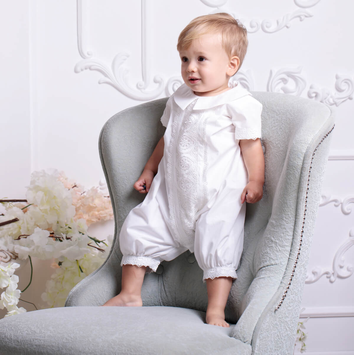 Baby Boy Baptism Romper sitting on a gray chair with a floral background