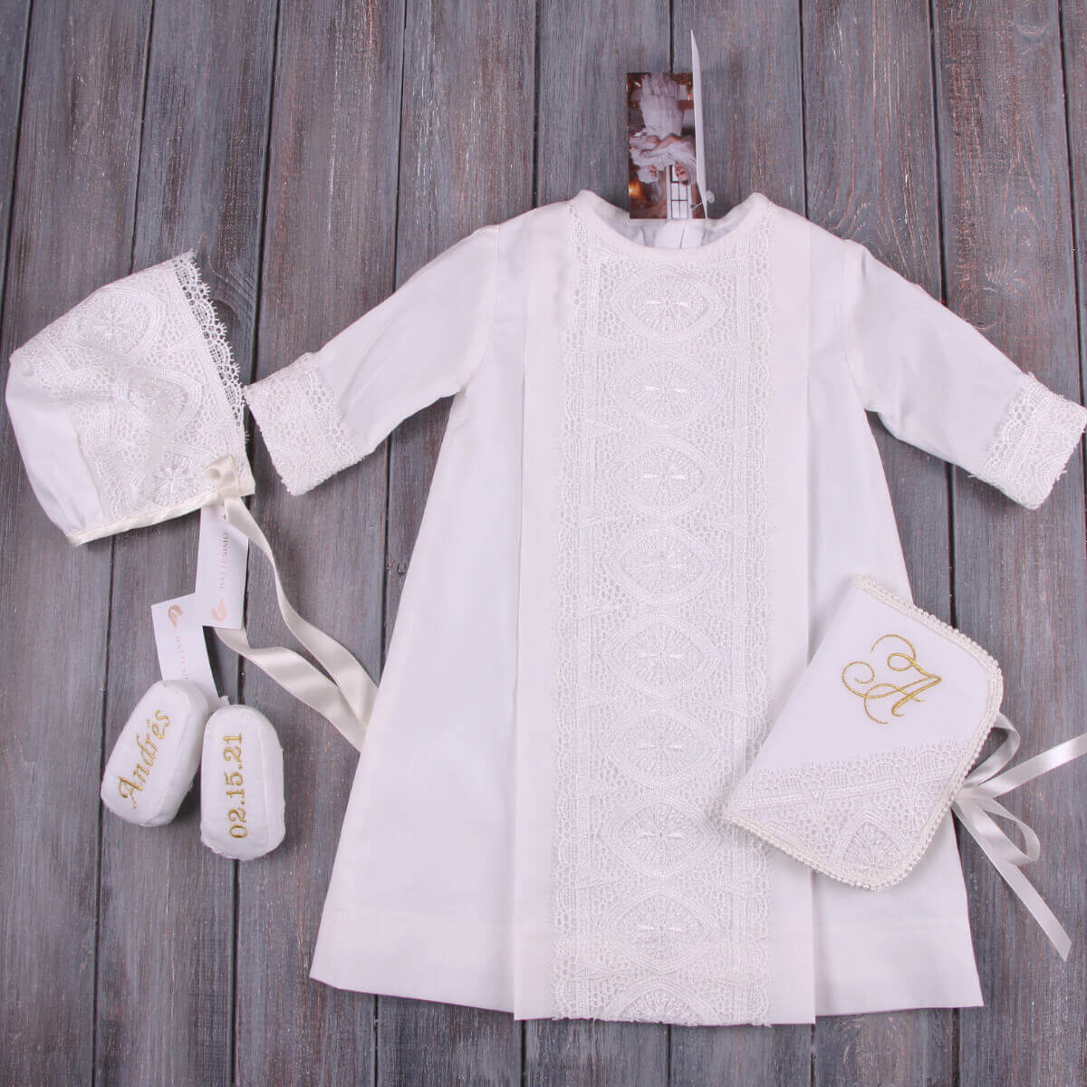 Boys Christening Outfit with bonnet, booties, and pouch on a wooden background