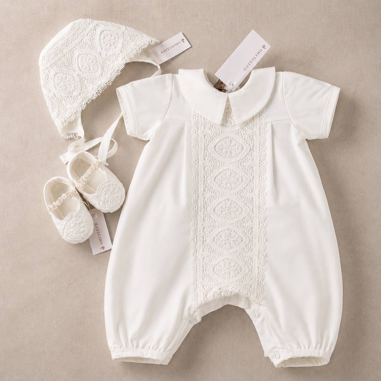 White baby baptism romper with matching hat and shoes on a beige background