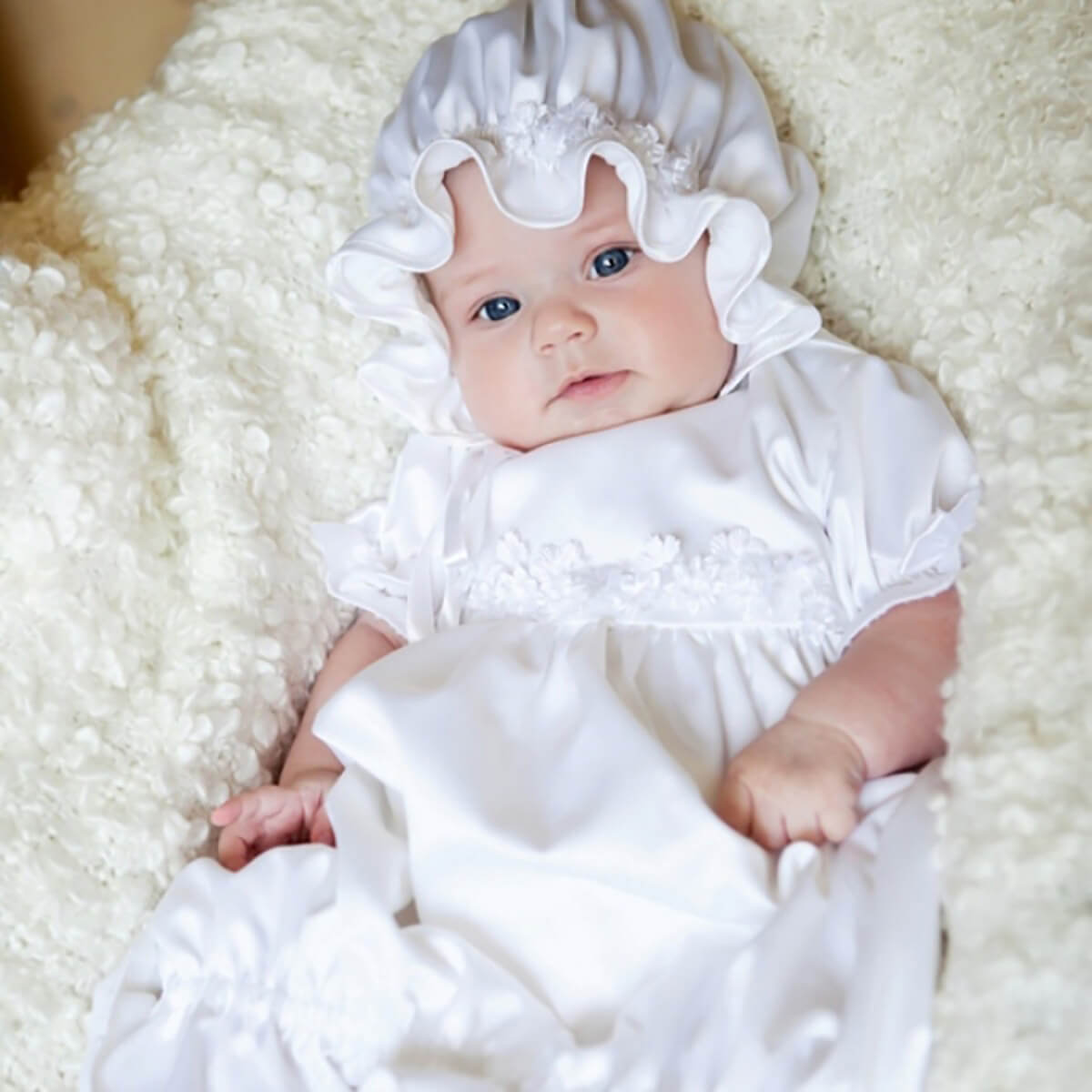Newborn Christening Gown with a bonnet on a soft, light-colored surface