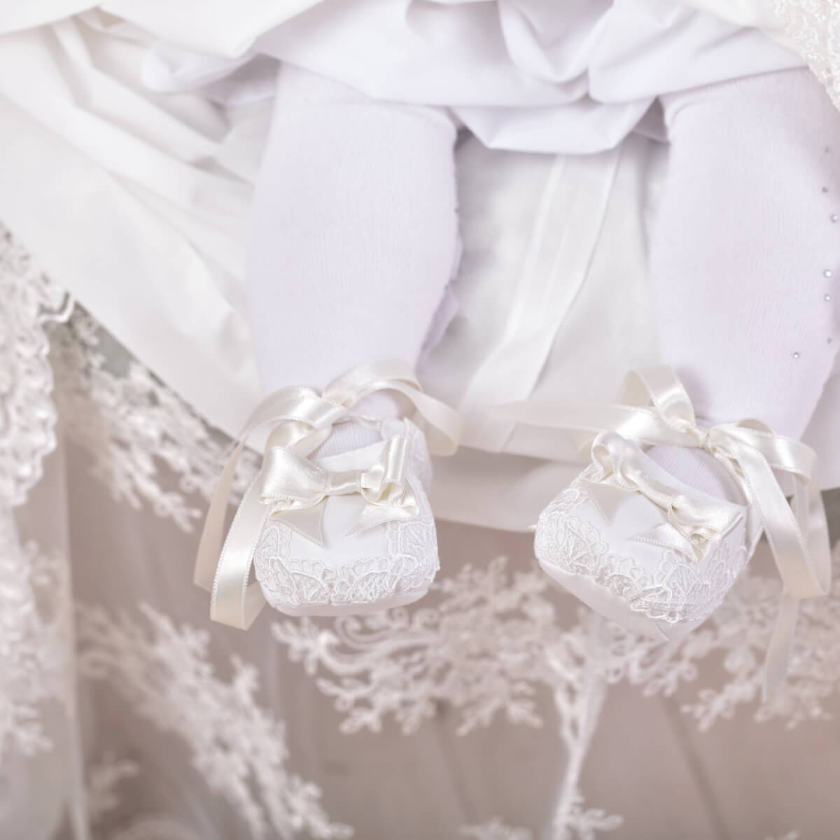 Christening Booties with ribbons on a textured white background