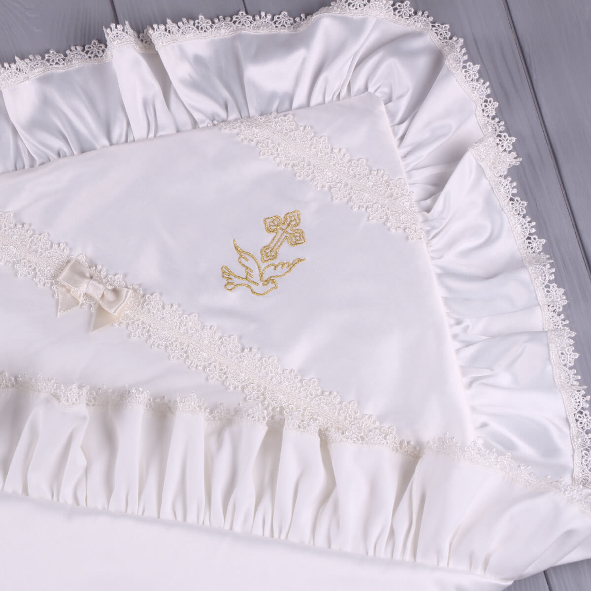 White embroidered christening blanket with gold design on a light gray background