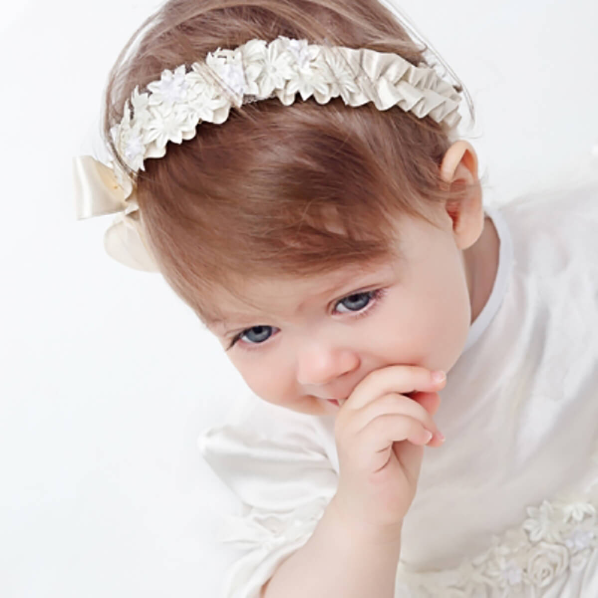 Girl wearing a decorative baby headband with a white background