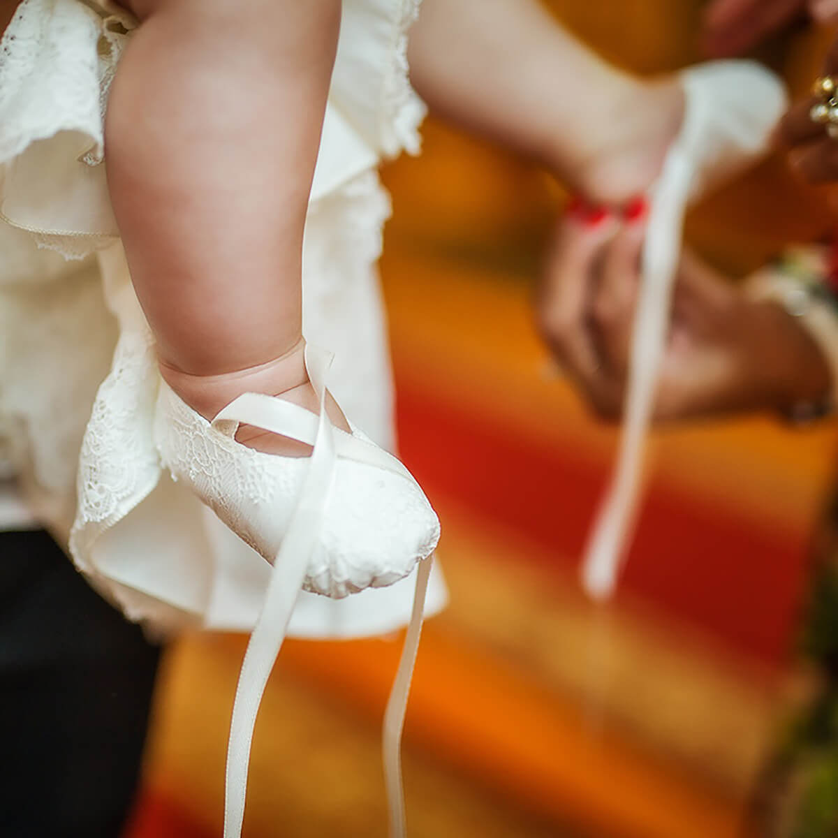 Christening Booties with ribbons worn by a child, blurred background